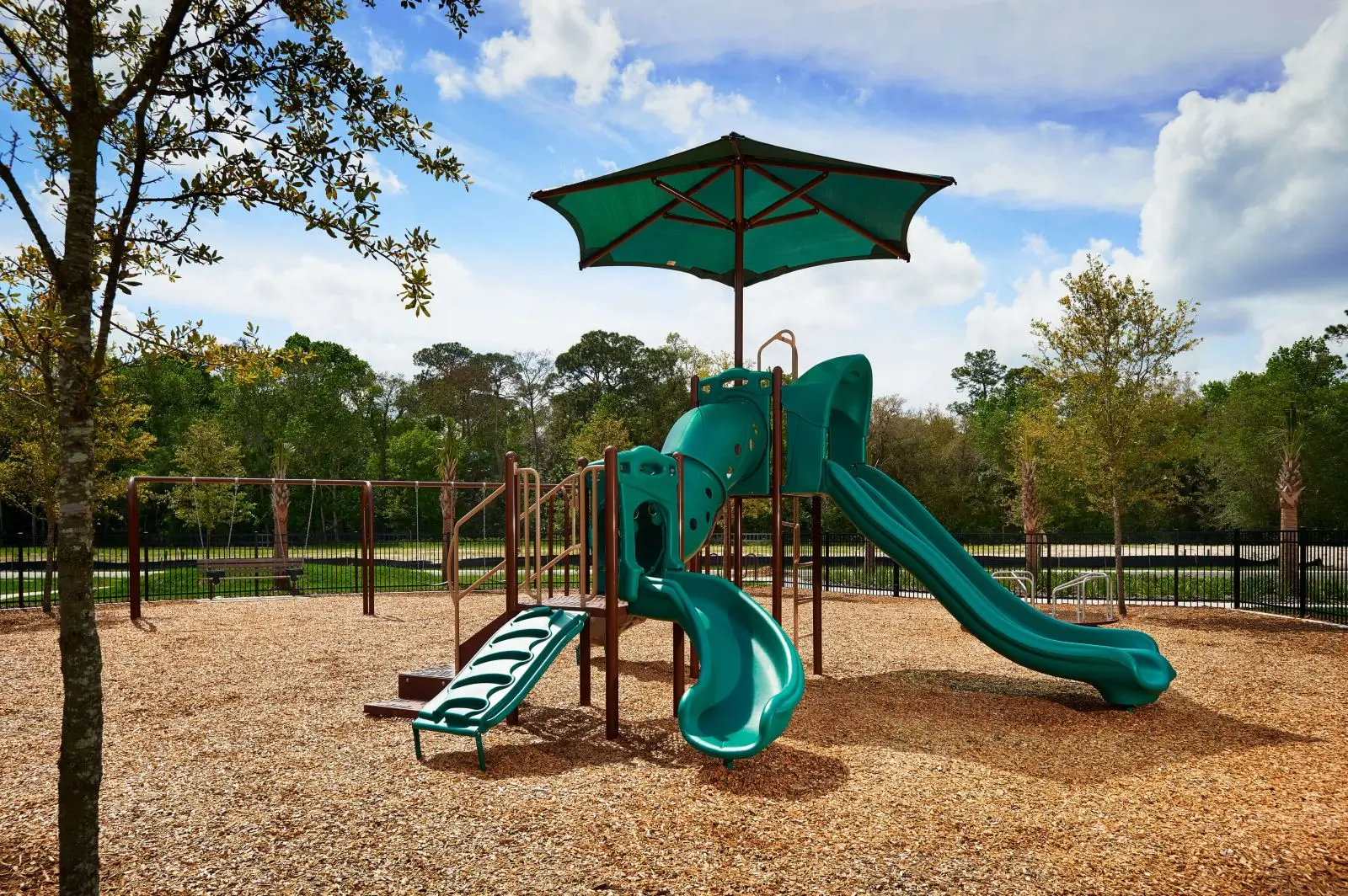A playground with slides and an umbrella.